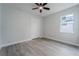 Bright bedroom featuring gray wood-look floors, ceiling fan, and natural light from the single window at 59 W 10Th St, Apopka, FL 32703