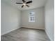 Bright bedroom featuring gray wood-look floors, ceiling fan, and natural light from the single window at 59 W 10Th St, Apopka, FL 32703