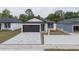 Charming home with a gray paved driveway, a black garage door, and manicured landscaping at 59 W 10Th St, Apopka, FL 32703