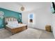 Bedroom with blue accent wall, wood bed frame, woven side table and patterned rug at 8951 Amelia Downs Trl, Kissimmee, FL 34747