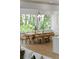 Dining room with a large wood table, modern light fixture, and large windows with a view of trees at 13562 S Lake Mary Jane Rd, Orlando, FL 32832
