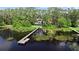 Scenic lake view featuring a private dock leading to an elegant waterfront home surrounded by lush green trees and vegetation at 13562 S Lake Mary Jane Rd, Orlando, FL 32832