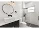 Sleek bathroom featuring a modern vanity, round mirror, and glass-enclosed shower with black fixtures at 16500 Magnolia Terrace Blvd, Montverde, FL 34756