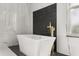 Close-up view of a modern white bathtub with gold fixtures and stylish black and white geometric tile accent wall at 16500 Magnolia Terrace Blvd, Montverde, FL 34756