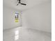 Simple bedroom with marble floors, ceiling fan, and a single window overlooking a green space at 16500 Magnolia Terrace Blvd, Montverde, FL 34756
