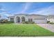 Well-maintained home featuring a pristine lawn, attractive arched entryway, and a two-car garage at 409 Belfry Dr, Davenport, FL 33897