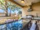 Covered outdoor kitchen with gas grill, countertops and a large glass top dining table at 7672 Amazonas St, Kissimmee, FL 34747