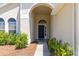 Inviting front entrance with an arched doorway, complemented by lush greenery and mature landscaping at 830 Grand Hughey Ct, Apopka, FL 32712