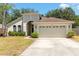Single-story home boasting an attached two-car garage, and a front lawn with beautiful greenery at 830 Grand Hughey Ct, Apopka, FL 32712