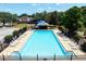 Community pool surrounded by lounge chairs, black metal fencing and greenery offers a relaxing oasis at 830 Grand Hughey Ct, Apopka, FL 32712