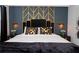 Elegant bedroom showcasing a black headboard with geometric gold detailing and decorative sconces at 9312 Sommerset Hills Dr, Davenport, FL 33896
