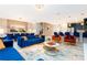 Open-concept living room featuring blue velvet sofas, a dining area, and a staircase at 9312 Sommerset Hills Dr, Davenport, FL 33896