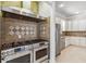 Modern kitchen featuring stainless steel double oven and hood, white cabinetry and stone back splash at 1013 Maiden Ter, Celebration, FL 34747