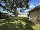 Backyard with mature trees and a glimpse of neighboring houses at 132 Acapulco Dr, Kissimmee, FL 34743