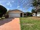 View of the home's exterior showcasing a two-car garage and a well-maintained front lawn at 132 Acapulco Dr, Kissimmee, FL 34743