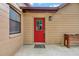 Close-up of the decorative front door of this tan home showing a red door with glass insert and decorative welcome mat at 150 Debary Dr, Debary, FL 32713