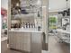 Chic bar area featuring mirrored backsplash, glass shelves, and stylish cabinetry for entertaining guests at 1761 Legion Dr, Winter Park, FL 32789