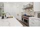 Modern kitchen featuring white cabinets, marble countertops, stainless steel appliances, and a stylish backsplash at 1761 Legion Dr, Winter Park, FL 32789