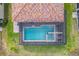 Aerial view of a private screened-in pool and spa with a brick paver patio and red tile roof at 2173 Lake Side Ave, Davenport, FL 33837