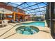 Backyard view of a large screened-in pool with a hot tub, outdoor furniture, and an umbrella at 2769 Lido Key Dr, Kissimmee, FL 34747