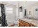 Bathroom with a granite vanity top, wood cabinetry, and shower-tub combo at 2769 Lido Key Dr, Kissimmee, FL 34747