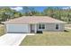 Inviting single-story home featuring a neatly manicured lawn, attached garage, and light beige exterior at 3914 Sw 161St Loop, Ocala, FL 34473
