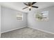 Minimalist bedroom showcases two windows, gray carpet, neutral walls, and a ceiling fan at 4070 Mcneil Rd, Apopka, FL 32703