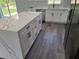 Kitchen featuring an island with quartz countertops, stainless steel appliances, white cabinets, and gray wood floors at 4529 Sw 169Th Pl, Ocala, FL 34473