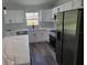 Kitchen featuring white cabinetry, stainless steel appliances, quartz countertops, and gray wood floors at 4529 Sw 169Th Pl, Ocala, FL 34473