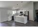 Modern kitchen with white cabinets, stainless steel appliances, island with marble countertops, and grey wood floors at 4529 Sw 169Th Pl, Ocala, FL 34473