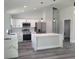 Open kitchen featuring white cabinets, stainless steel appliances, island with marble countertops, and gray wood floors at 4529 Sw 169Th Pl, Ocala, FL 34473