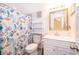 Neat bathroom with a floral shower curtain, bright mirror, and functional storage shelves at 5325 Hansel Ave # E-15, Orlando, FL 32809