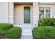 Close-up of the townhome's entrance with a dark green door, landscaped bushes, and clean concrete steps at 6013 Blue Lily Way, Winter Garden, FL 34787