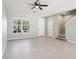 Open-concept living area with neutral-toned tile flooring, ceiling fan, stairs and a large window, offering ample light at 6013 Blue Lily Way, Winter Garden, FL 34787