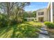 Expansive backyard featuring a lush lawn, mature trees, and a modern home with large windows at 608 E Club Cir, Longwood, FL 32779