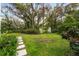 Lush backyard featuring green lawn, mature trees, and a quaint garden gate, creating a serene outdoor space at 608 E Club Cir, Longwood, FL 32779
