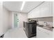 Bright laundry room equipped with modern black washer and dryer, sink, and ample storage in white cabinets at 608 E Club Cir, Longwood, FL 32779