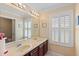 Bathroom featuring a double vanity, neutral countertop, and window with plantation shutters at 6857 Dolce St, Orlando, FL 32819