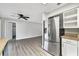 Open-concept living room with sleek gray flooring, ceiling fan, and stainless steel refrigerator at 7507 Duo Lakes Dr, Orlando, FL 32810