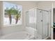 Bathroom showcasing a soaking tub next to a glass enclosed shower, complimented by a view through the window at 802 Pickfair Ter, Lake Mary, FL 32746
