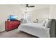 Cozy bedroom features a ceiling fan, large window with blinds, and a bed with an adjacent red dresser at 8448 Greenbank Blvd, Windermere, FL 34786