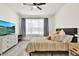 Bright bedroom features a ceiling fan, large window with curtains, and a stylishly decorated bed and dresser at 8448 Greenbank Blvd, Windermere, FL 34786