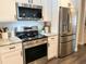 Stainless steel appliances and modern white cabinets in renovated kitchen at 8484 Sandberry Blvd, Orlando, FL 32819