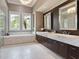 A spacious bathroom with a marble-encased tub and elegant vanity with dual sinks beneath stylish mirrors at 8581 Lake Nona Shore Dr, Orlando, FL 32827