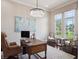A well-lit home office with a large desk, leather chair, and elegant chandelier at 8581 Lake Nona Shore Dr, Orlando, FL 32827