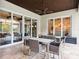 Covered patio with travertine flooring, ceiling fan, and multiple dining tables, perfect for outdoor gatherings at 8581 Lake Nona Shore Dr, Orlando, FL 32827