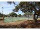 Well-maintained tennis court with a lake view, shaded by mature oak trees with Spanish moss at 8830 Ladrido Ln, Orlando, FL 32836