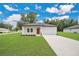 Charming single-story home featuring a two-car garage, a neatly manicured lawn, and a bright, orange front door at 9472 Se 152Nd Pl, Summerfield, FL 34491