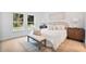 Serene bedroom with plush bedding, stylish bedside tables, wood-look floors, and large windows with backyard views at 9472 Se 152Nd Pl, Summerfield, FL 34491