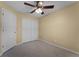 Bedroom with carpet, closet, door, and yellow painted walls and ceiling fan at 16064 Old Ash Loop, Orlando, FL 32828